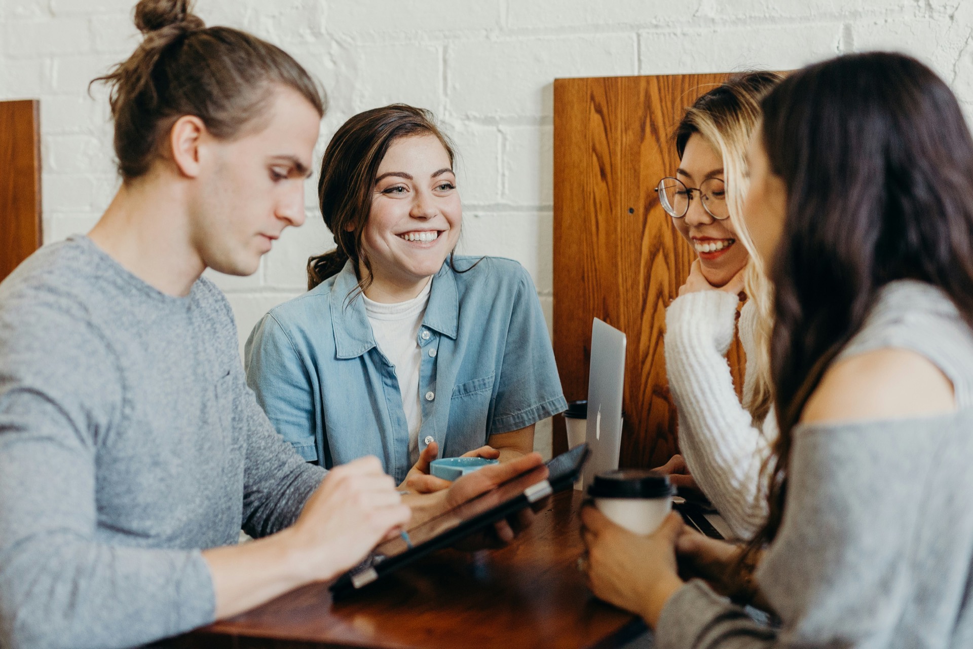Four friends talking and laughing around a café table